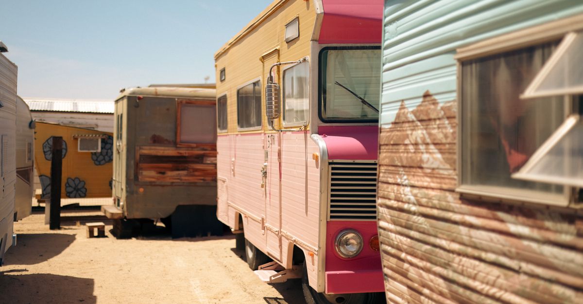 A row of vintage campers under a clear sky in Joshua Tree, California.